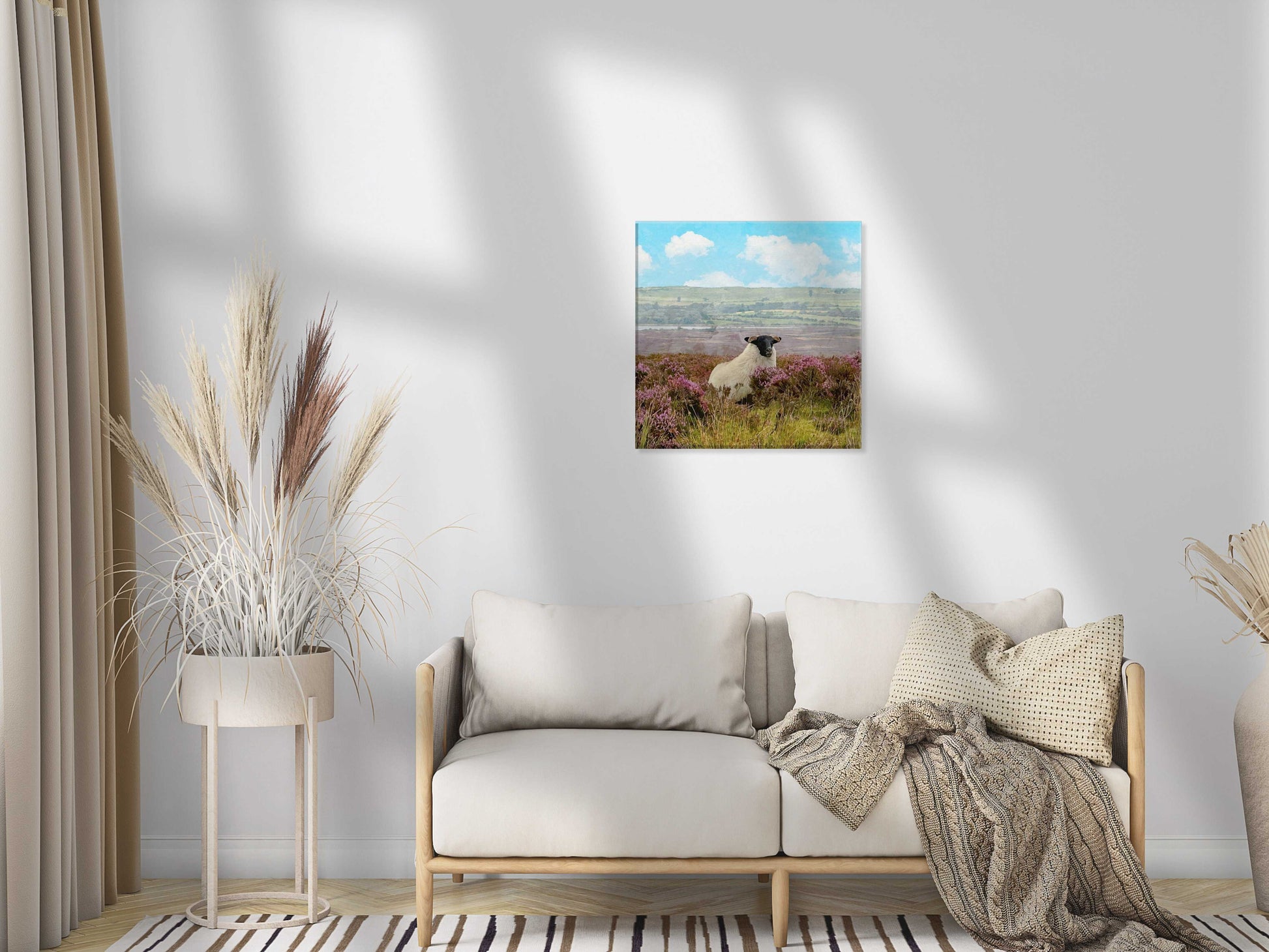 Living room with a sofa, decorative plants, and a framed picture of a sheep in a field.